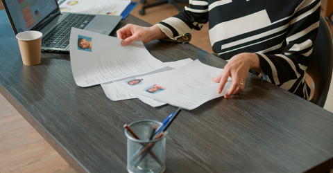 Werkgeefster bekijkt sollicitatiebrieven achter bureau met laptop